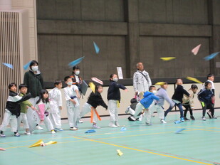 子どもたちが紙飛行機を飛ばしている写真