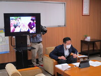 写真:会場においてテレビ電話で高齢者の方と会話をする様子